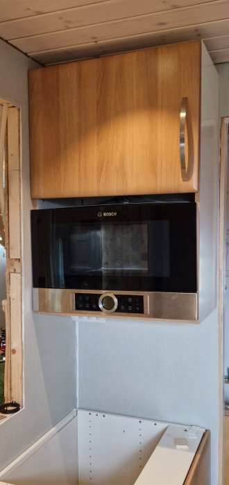 En mikrovågsugn från Bosch monterad under ett överskåp i ett delvis renoverat kök.