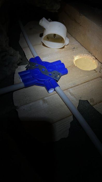 Installation av takdosa i mörk vind med synliga isoleringsmaterial och elrör.