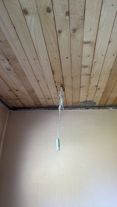 Träpaneltak med en elektrisk takdosa och ledningar i ett renoveringsprojekt.