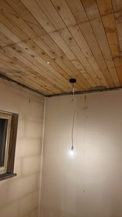 Träpaneltak med ny eldosa och tillfällig belysning i en byggarbetsmiljö.