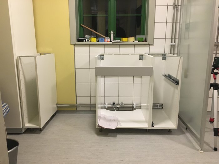 Badrum under renovering med halvbyggd tvättbänk under fönster och en blandare installerad.