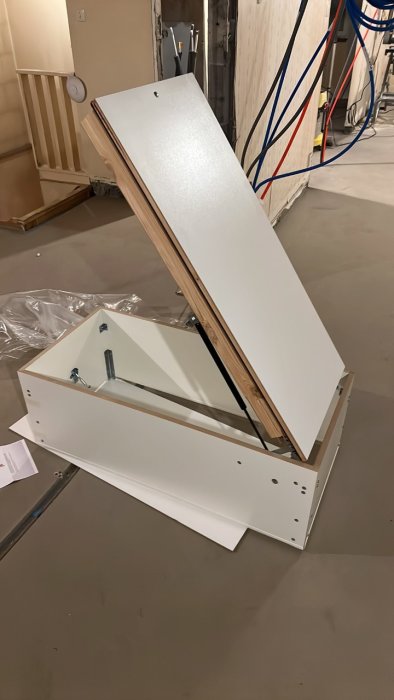 Komponenter till en ny vindslucka installerad i en hall, med en öppen stege och en överlucka.