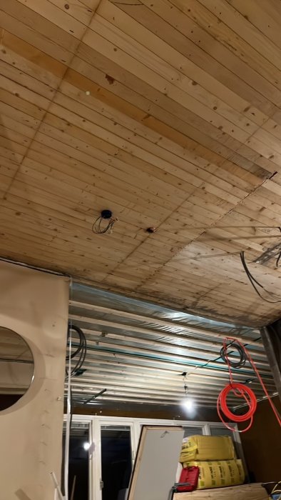 Träpaneltak med markerade hörnpunkter och kablar inför installation av ny vindslucka.