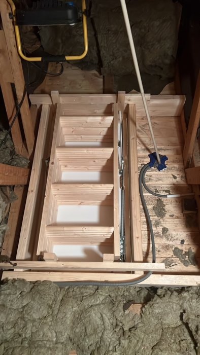 Installerad vindslucka av trä i takram utan isolering, med sticksåg och förlängningssladd.