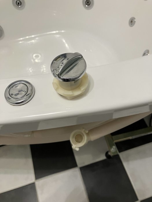 Ett vred för luftintag på kanten av ett jacuzzibadkar med synliga jetmunstycken och en del av badkarsfronten.