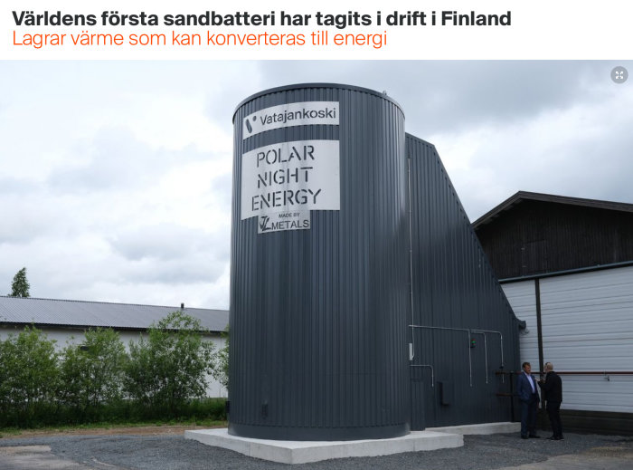 Ett stort grått sandbatteri med texten ”Polar Night Energy” och några personer som står utanför i Finland.