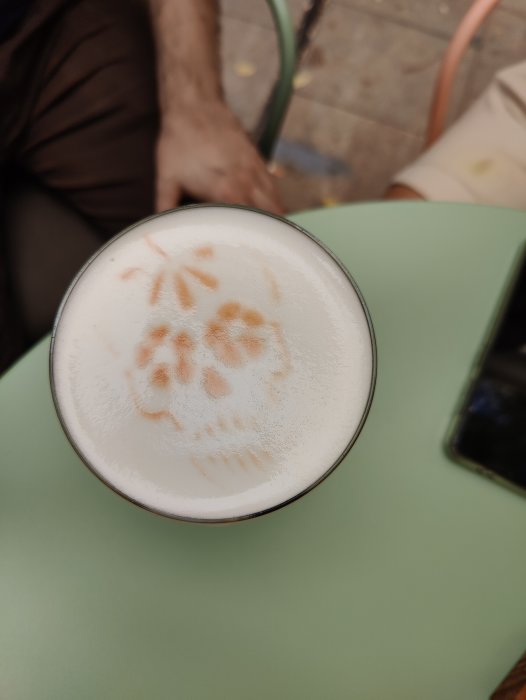 Glas med skummande Mojito och dekorativt avtryck på ytan, på ett grönt bord.
