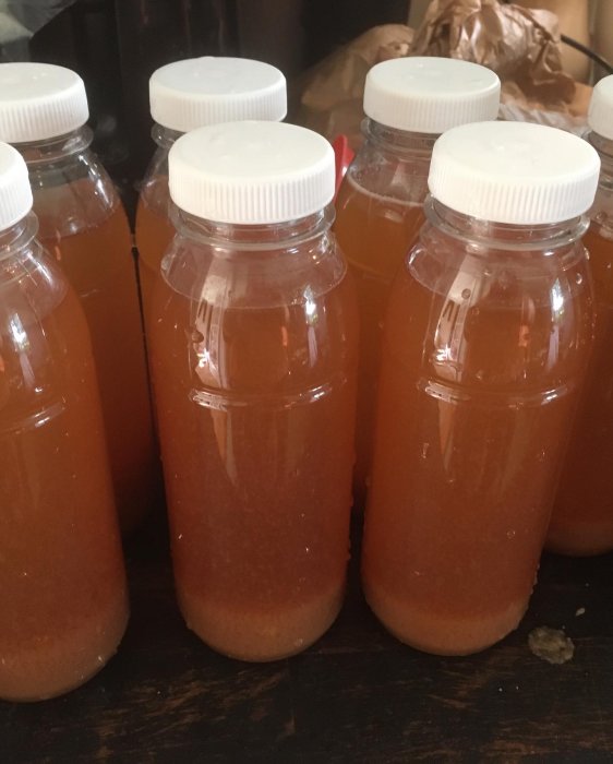 Flaskor med nypressad, fryst äppeljuice på ett bord, beskrivna som "sommar på flaska".