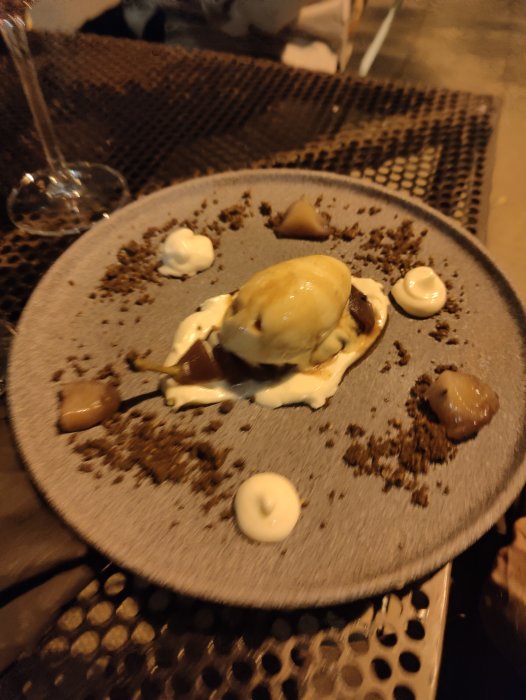 Tallrik med ål och anklever anrättning, garnerad med klickar och smulor, serverad utomhus.