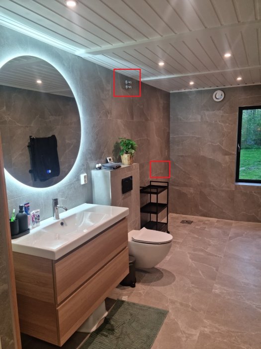 Modern badrum med kaklade väggar, trädetaljer, tvättställ, toalett och handdukshängare.