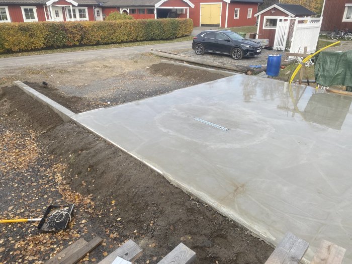 Nyutgjuten betongplatta för husgrund med avlägsnad gjutform och verktyg synligt.