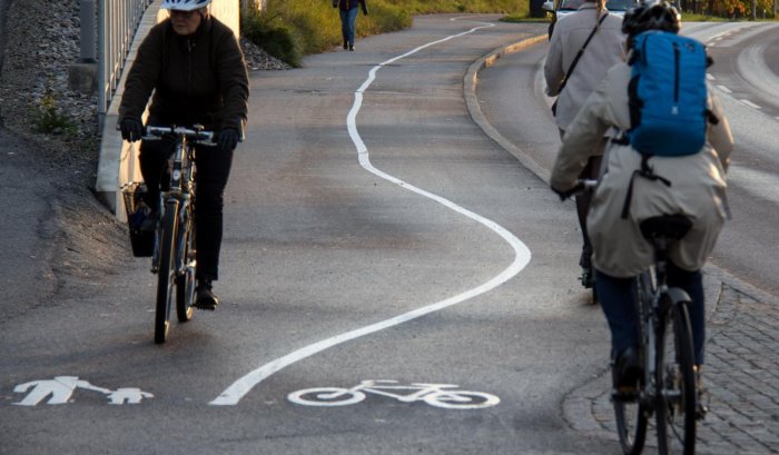 Cykelbana med slingrande vit linje och cyklister som följer banan.