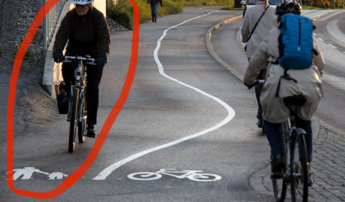 Cykelväg med slingrig linje och röd markering, cyklister i rörelse.