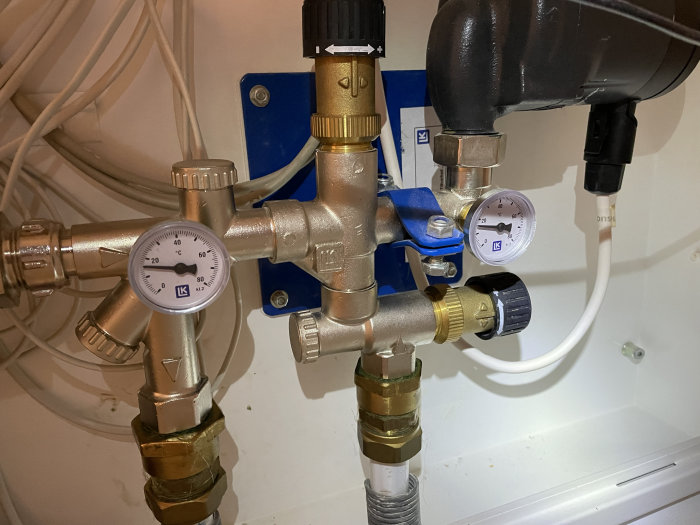 VVS-installation med mätare och rörkopplingar inne i ett skåp.
