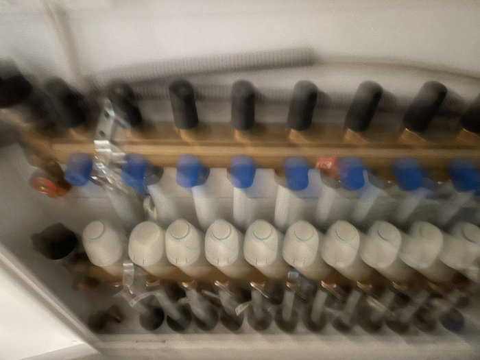 Suddig bild av rör och ventiler i ett värmesystem under installation.