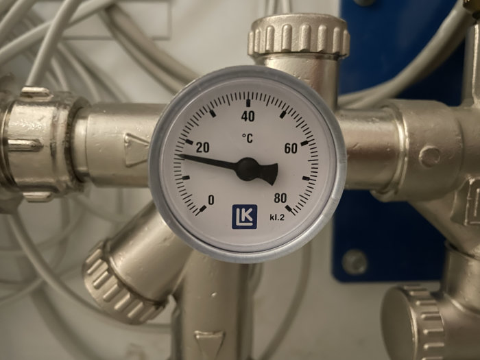 Temperaturmätare från LK visar cirka 40 grader Celsius på en värmesysteminstallation.