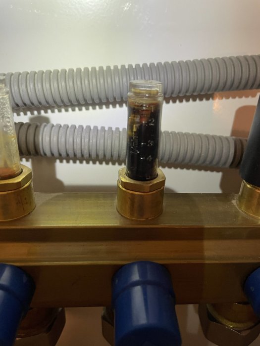 Avstängningsventil till värmesystem med synlig smutsig vätska i genomskinligt inspektionsrör.