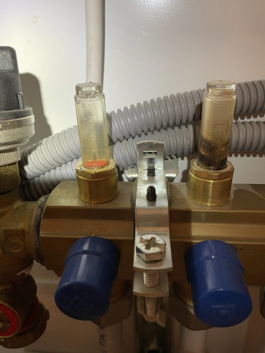 VVS-installation med mätglas för vattenflöde och blå ventilkåpor.