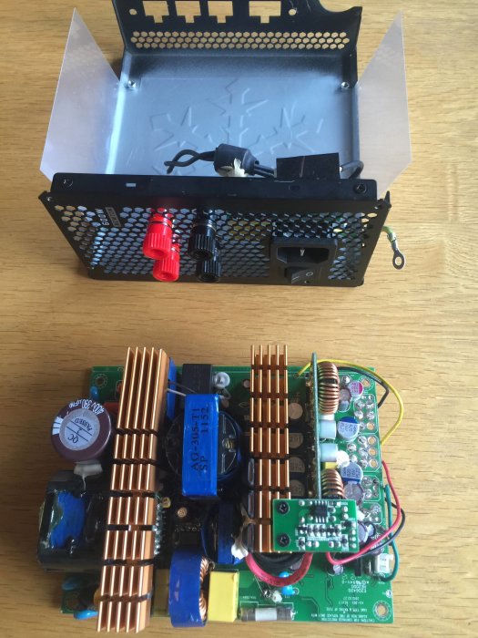 Modifierat nätaggregat med bortlödda delar och eftermonterade banankontakter på träbord.