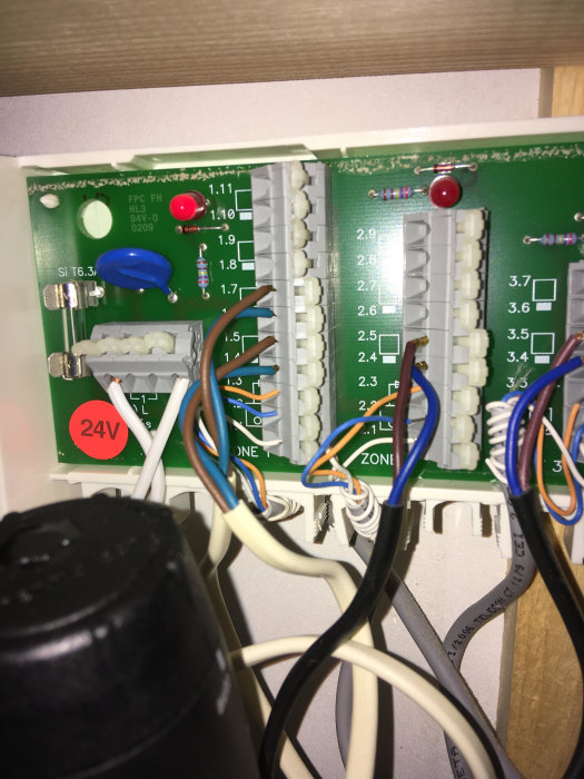 Elektronisk kretskort-panel med märkta anslutningar och flera inmatade kablar synliga.