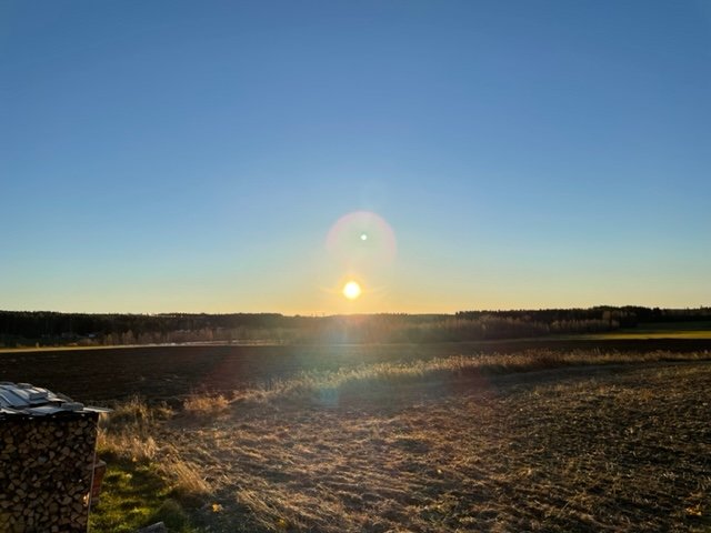 Solnedgång över öppna ängar utan skuggande objekt synlig från taket med solpaneler.