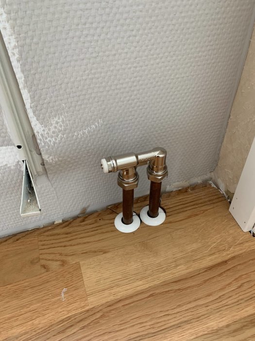 Nyligen installerad klämkoppling på två kopparrör vid en isolerad vägg, redo för värmepumpsbyte nästa vinter.