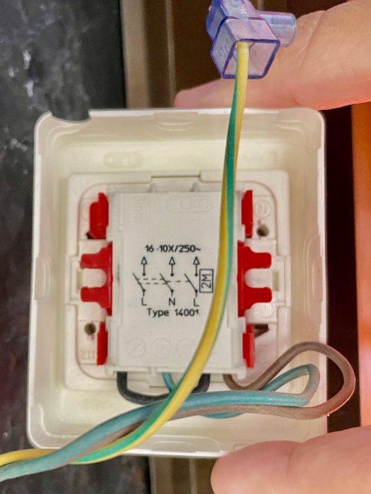 Närbild på en hand som håller en ansluten eldosas insida med trådar och anslutningsschema synligt.