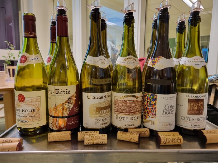 Flaskor av Cote Rotie-viner uppradade med korkar framför, tema för vinprovning.