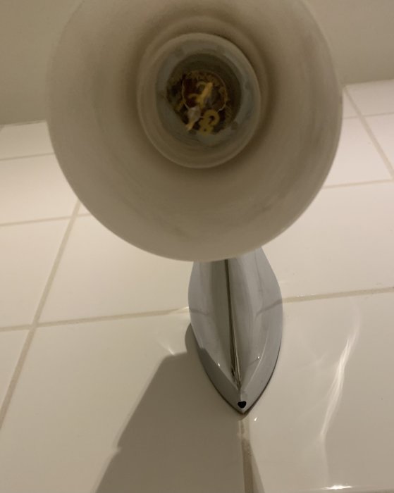 Vy inifrån en toalettskål ner mot öppen spolmekanism och vatteninlopp.