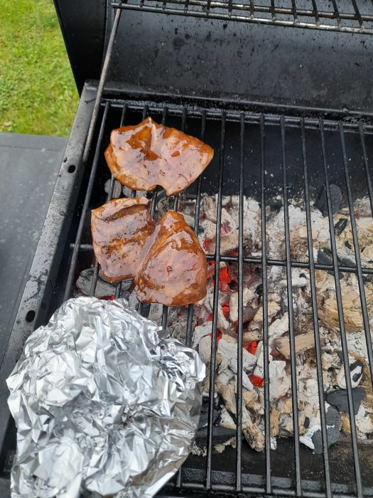 Lammhjärta grillas på kolgrill med inslaget foliepaket, potentiellt innehållande potatis eller grönsaker.