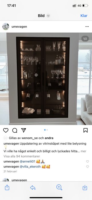 Inbyggt vitrinskåp med belysning och glasade dörrar visar glas och flaskor, mot en bakgrund av ett vardagsrum.