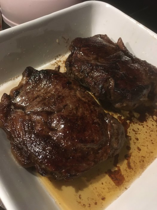 Två stekta biffar med lägre marmoreringsgrad i en vit skål.