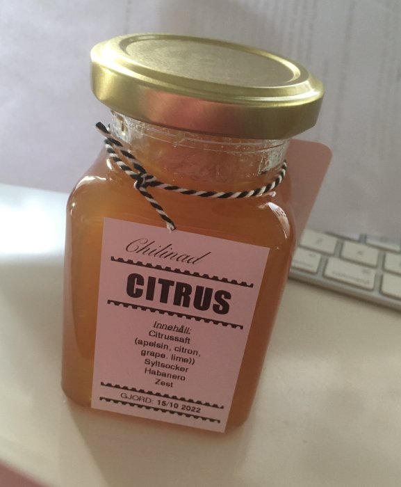 Hemgjord citrusmarmelad i burk med etikett som lister ingredienser och tillverkningsdag.