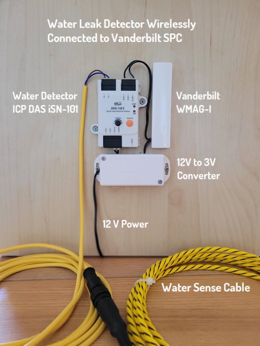 Vattenläckagedetektor och konverteringsenheter monterade på träpanel med ansluten gul sensorledning.