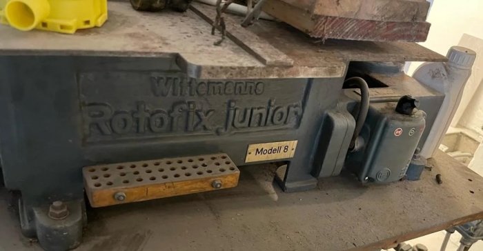 Centrifug utrustning märkt med 'Witeg Labortechnik Rotofix Junior Modell 8' på ett dammigt arbetsbord med byggmaterial.