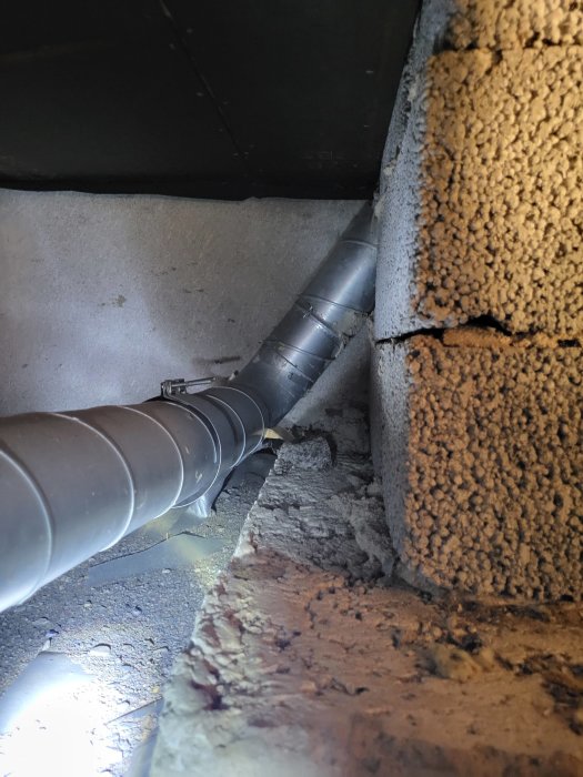 Rörledning för ventilation under krypgrund med synligt fundament och isolering.