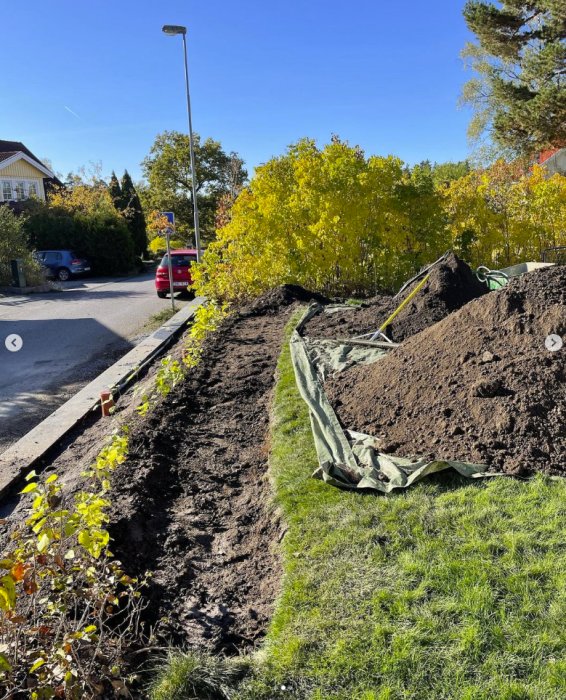 Grävd dräneringsdike intill uppfart med synliga dagvattenkassetter och markduk.