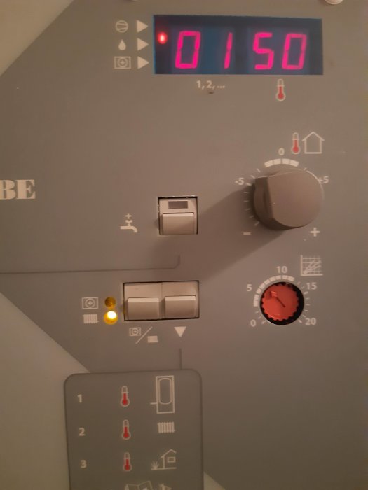 Digital termostat visar 15 grader Celsius med justeringsknappar och indikatorlampor.