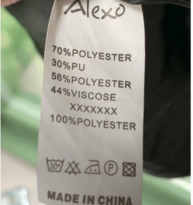 Tygetikett som visar materialinnehåll och skötselråd, inkluderar polyester och viskos, samt tvättsymboler.