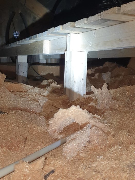 Förstärkt takstol med nya reglar och panelbrädor som golv, omgiven av isoleringsmaterial.