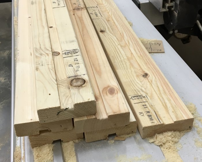 Träplankor med utmätta snitt och kapade ändar, förberedda för att bygga skåpstommar.