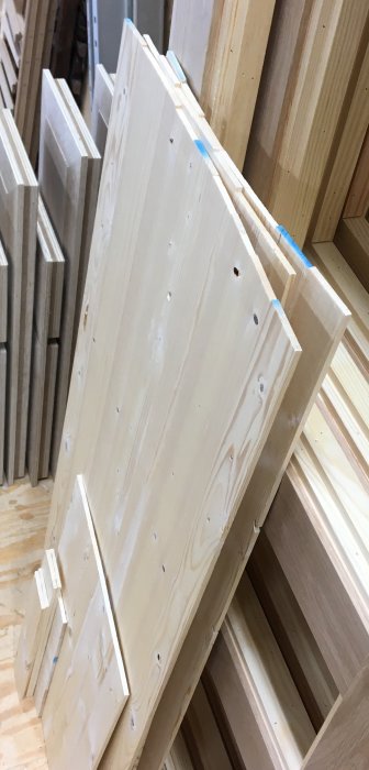 Hyllkomponenter i trä med frästa spår och limmade tappar, bearbetade och redo för skåpsmontering.