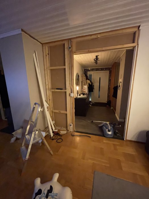 Vägg under rivning med synlig trästomme och rivningsmaterial samt verktyg på golvet.