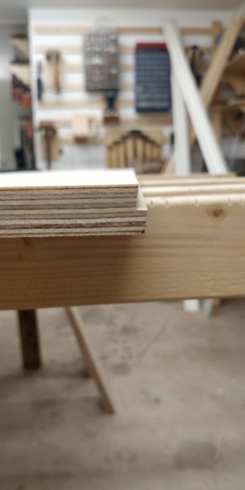 Närbild av plywoodkanten med en fals i en verkstadsmiljö.