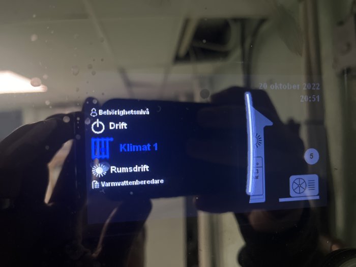 Skärmvisning av temperaturstyrningspanel med reflekterad spegelbild av en person.
