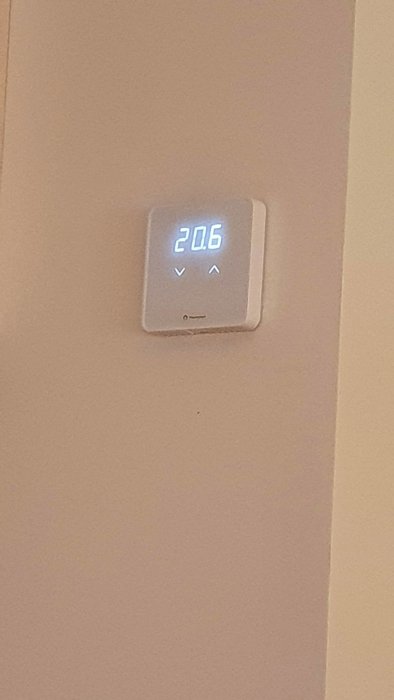 Digital termostat på vägg visar 20.6 grader Celsius.