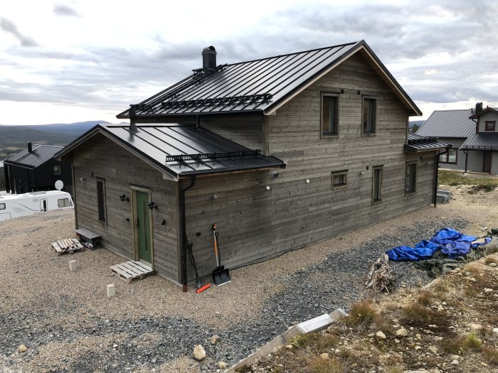 Ett nyligen panelat hus med svart tak och behandlad fasad, visar byggprojektets resultat sept 2021 - okt 2022.