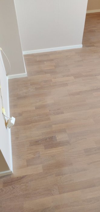 Nyinstallerat laminatgolv med ljus ekfinish och vita fotlister.