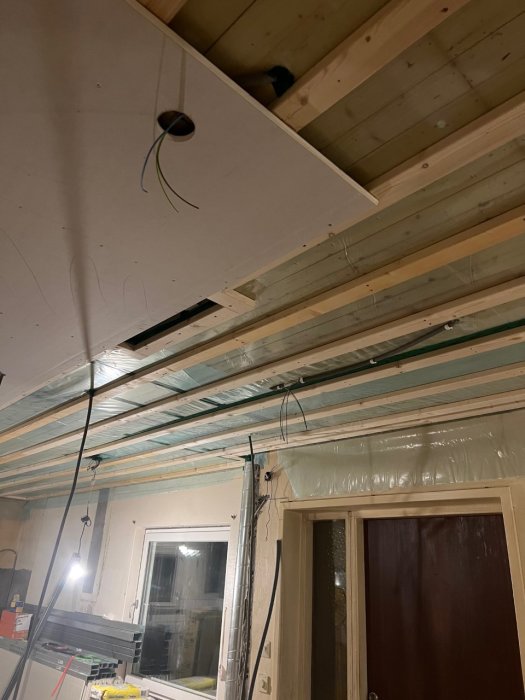 Gipsvägg under konstruktion med utmärkta platser för spotlights och utstickande slangar i taket.