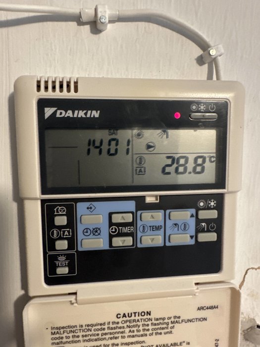 Digital termostat för värmepump märkt Daikin som visar rumstemperatur 28.8°C och tid 14:01.